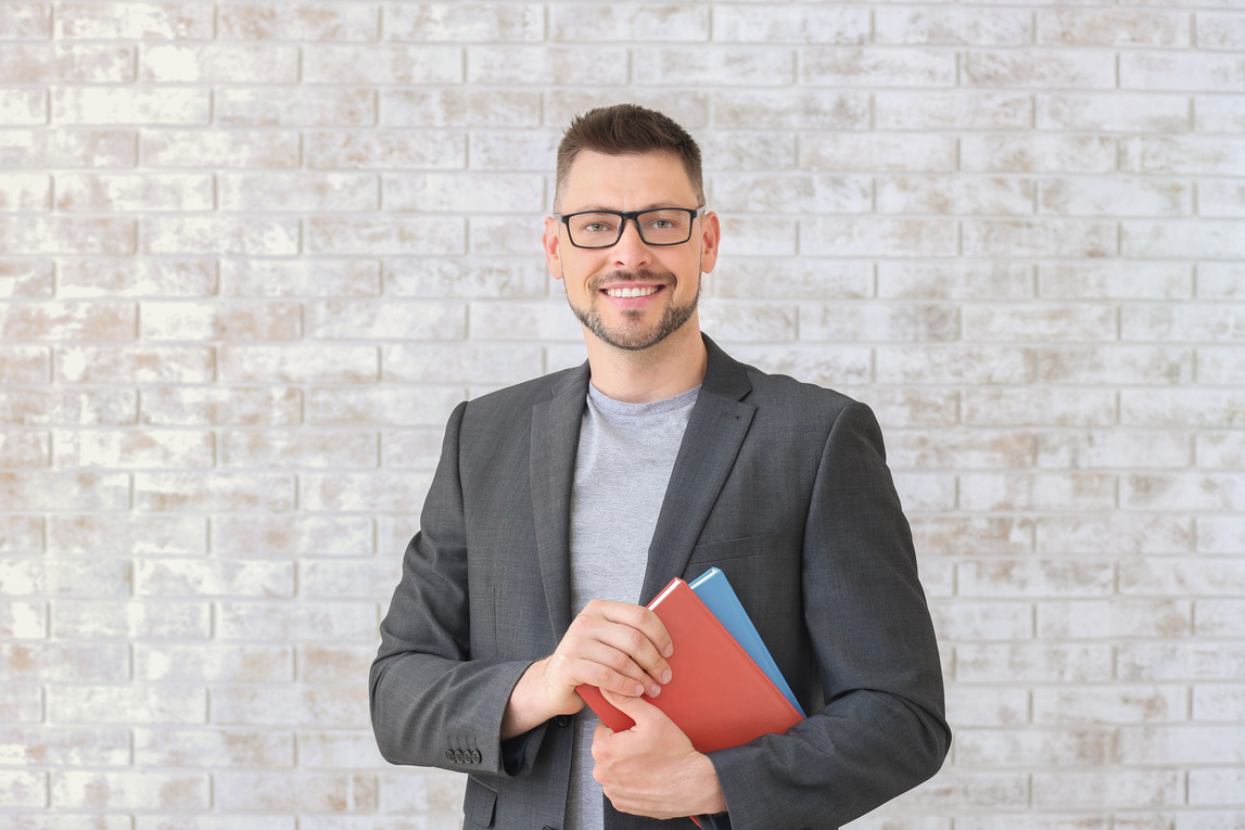 Handsome Male Teacher against Brick Wall